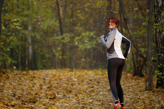 Image of happy woman in sports clothes on run in autumn