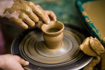 Fototapeta premium Sculpts in clay pot closeup. Modeling clay close-up. Caucasian man making vessel daytime of white clay in fast moving circle. Art, creativity. Ukraine, cultural traditions. Hobbies