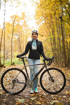 Image of woman in helmet, jeans next to bicycle