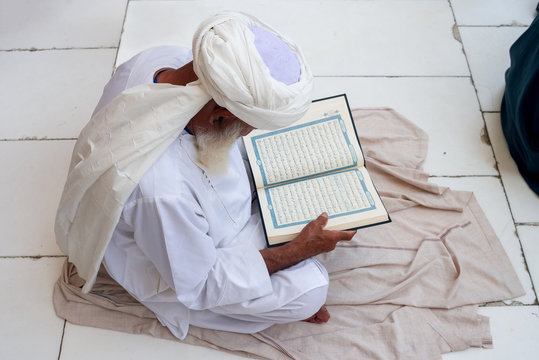MECCA, SAUDI ARABIA - MAY 02 2018: Old man sitting in Masjid Al Haram near Holy Kaaba, reading Quran before Prayer Time