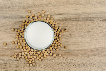 Obraz na płótnie Canvas top view of a glass of soy milk and a pile of soybeans on the wooden table.