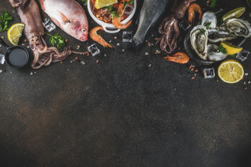 Fresh raw seafood squid shrimp oyster mussels fish with spices of herbs lemon on dark rusty background copy space top view