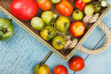 Set of ripe tomatoes in the wooden tray