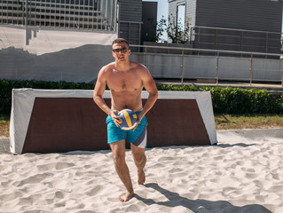 Volleyball beach male player getting ready to serve the ball on the beach.