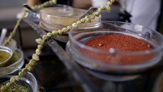 panorama of metal rack with glass plates filled of different kind of spices on a market