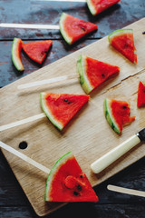 Fresh organic watermelon slice popsicles on rustic wooden board and dark rustic woodenbackground. Selective focus. Tasty summer fruit, healthy lifestyle