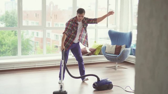 Funny man doing the cleaning vacuums and have fun dancing