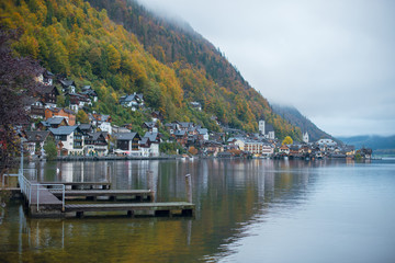 Fototapeta na wymiar Beautiful autumn view of Hallstatt lake, mountains and village with houses and church in Austria. Foggy weather.