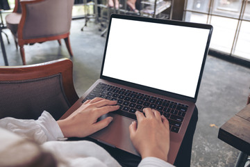 Mockup image of a woman using and typing on laptop with blank white desktop screen while sitting in cafe