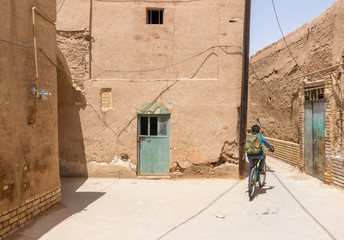 YAZD, IRAN - MAY 2, 2017. A small boy riding his bike on the streets of Yazd old town. Authentic and beautiful photo, warm Persian and Arabic style and atmosphere