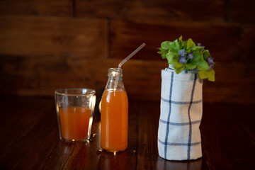 vintage bottle with juice, straw, flowers and towel on wooden table