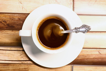 white cup of coffee on a saucer on a wooden background