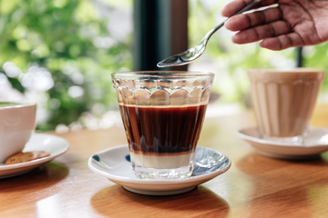 Hot served Vietnamese coffee that can wake you up: Black coffee mix with condense milk in clear glass served on wooden table 