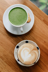 Top view of Latte art heart shape and green tea latte served on wooden table. Smooth and refresh when drinking.