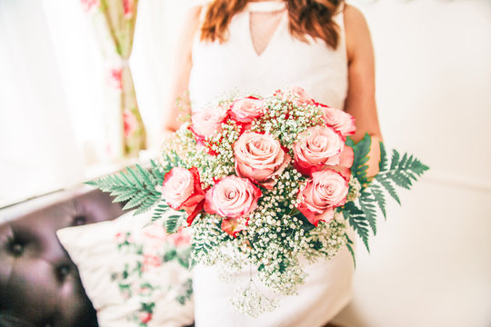 Newly Wed Woman Holding her Bridal Bouquet with Wedding Rings on a Rose.