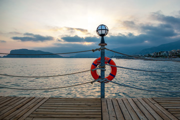 Fototapeta premium pier with lamp and lifebuoy at sunset