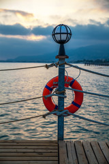 Fototapeta premium pier with lamp and lifebuoy at sunset