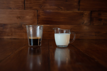 milk in glass milk jug with a cup of coffee in a transparent glass