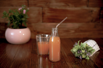 vintage bottle with juice, straw, flowers and towel on wooden table