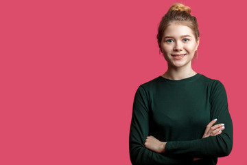 Young smiling blond woman in casual clothing against pink wall with copyspace area for advertise...