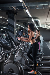 Fototapeta na wymiar Young woman training on cross trainer at the gym