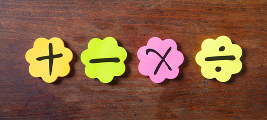 Sticky colorful notes in flower shape, isolated, with math symbols on wooden background.