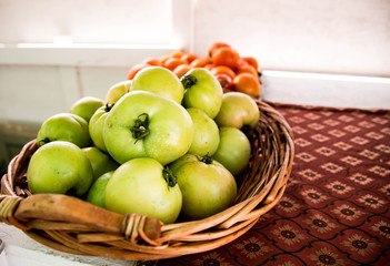 Green tomatoes in basket in foreground
