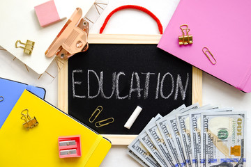Investing money in expensive education, college tuition & fees concept. Pack of new one hundred dollar bills, notebooks, school supplies, black chalk board. Background, copy space, close up, flat lay