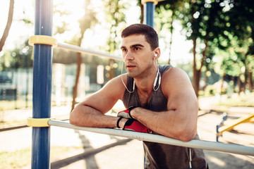 Obraz premium Male athlete poses on horizontal bar outdoor