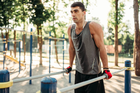 Male athlete exercises on parallel bars outdoor