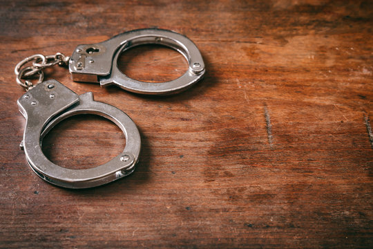 Handcuffs isolated and copy space on a wooden background.