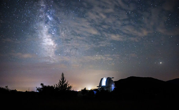 Open dome of a big telescope in an observatory in the background of the starry sky