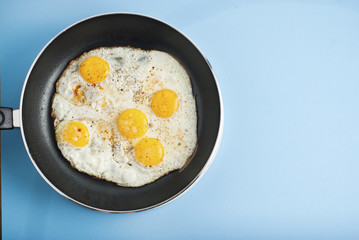 Breakfast Food Fried one egg in a frying pan isoalted on blue background copy space for text