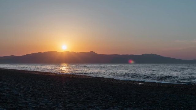 Timelapse of kids playing and taking photos of the sunset on the beach.