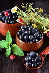 Bilberries in wooden bowls against the dark background