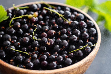 Blackcurrant berries with leaves, blackcurrant in a bowl.