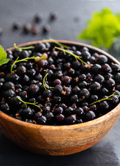 Blackcurrant berries with leaves, blackcurrant in a bowl.