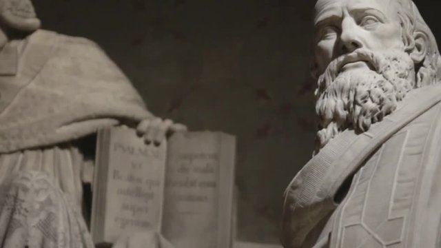 Handheld shot of dramatic statues in old french church under spotlights