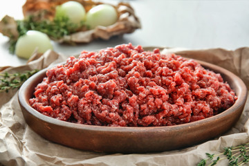 Wooden plate with fresh forcemeat on table