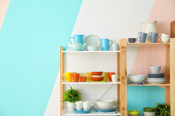 Kitchen shelving with dishes on color wall background