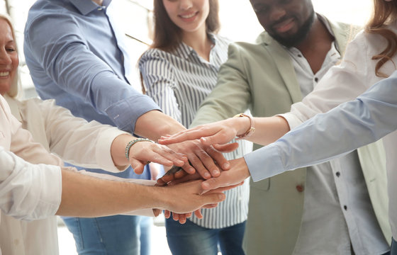 People putting hands together indoors. Unity concept