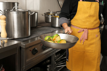 Male chef cooking vegetables in restaurant kitchen
