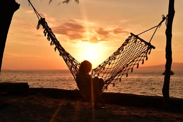 Crédence de cuisine en verre imprimé Mer / coucher de soleil Siilhouette of woman sitting in hammock at sunrise on the beach, Gili Meno Island, Lombok, Indonesia