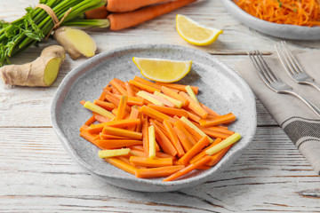 Plate with tasty carrot salad on wooden table