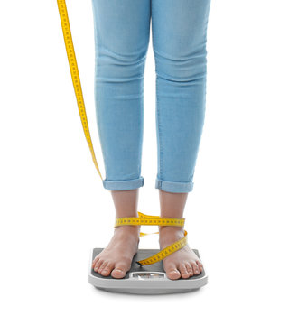 Woman with tape measuring her weight using scales on white background. Healthy diet