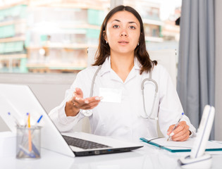 Practicioner girl in medical uniform is working with documents and laptop