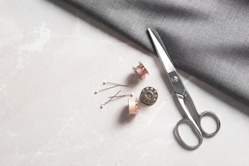 Bobbins with threads, fabric and scissors on table, top view. Tailoring accessories