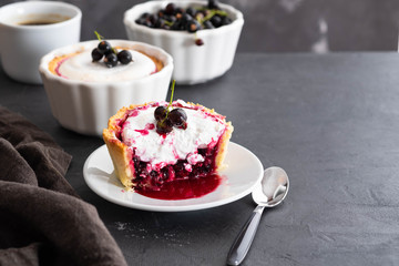 Pie with fruit and berry filling and meringue with a cup of coffee on a black background.