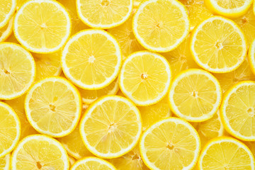 A slices of fresh juicy yellow lemons.  Texture background, pattern. - obrazy, fototapety, plakaty