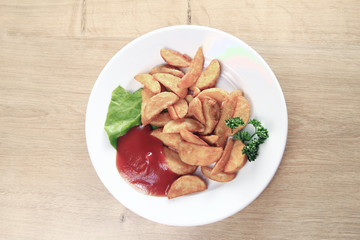 fried potatoes and sauce on a white plate in the wooden background